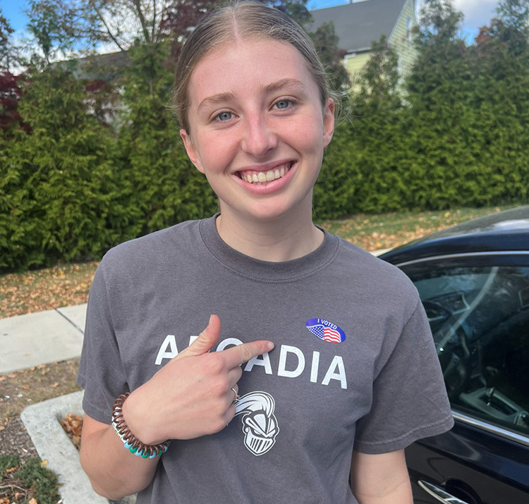 Shelby Jones '26 smiles for the camera while pointing to an "I Voted" sticker she is wearing.
