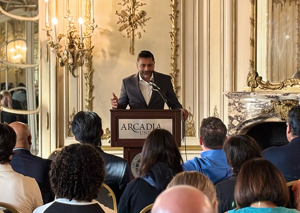 President Ajay Nair stands at a podium delivering welcome remarks