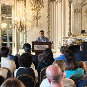 Dr. Raghu Kurthakoti stands at a podium delivering welcome remarks