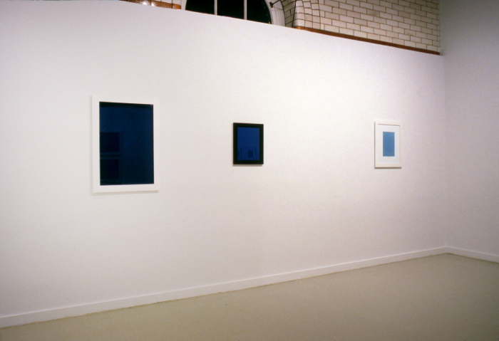 Photo of a white wall with blue paintings on it.