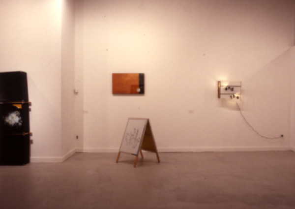 Photo of a white room with a painting standing in the middle and a light up frame on the right