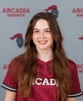 Honors Convocation 2026 award recipient Molly Delio stands in front of an Arcadia University-themed backdrop and smiles while wearing an Arcadia shirt.