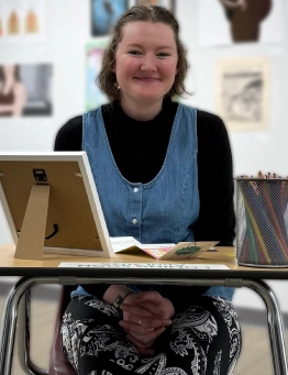 Honors Convocation 2026 award recipient Rebecca Hoyer sits in a desk and smiles.