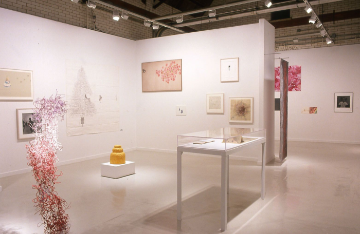 Photo of an exhibit with a yellow bot on a platform and many sculptures and paintings with cherry blossoms.