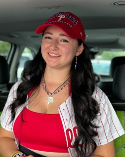 Honors Convocation 2026 award recipient Amanda Meissler sits in a car with a Phillies jersey and hat on and smiles.