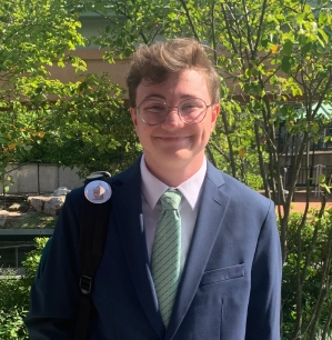 Honors Convocation 2025 award recipient Elliot Lawrence Vasey stands outside in front of trees and smiles.