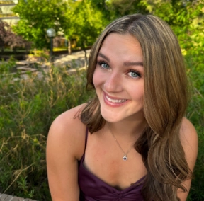 Honors Convocation 2025 award recipient Haylee Kos sits outside surrounded by greenery and smiles.
