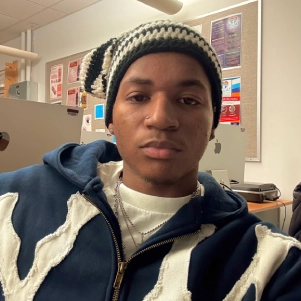 Honors Convocation 2025 award recipient Isaiah Anthony Heard takes a selfie with a beanie on in a classroom.