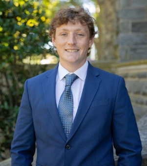 Honors Convocation 2026 award recipient Jacob Mann stands in front of the Grey Towers Castle and smiles.