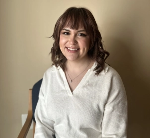 Honors Convocation 2025 award recipient Jenna Maria Hill sits in a chair and smiles.