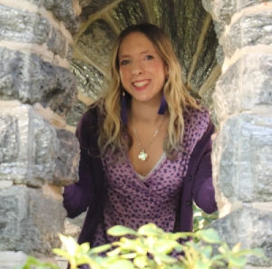 Honors Convocation 2025 award recipient Joanne McGinniss stands behind a stone arch and smiles.