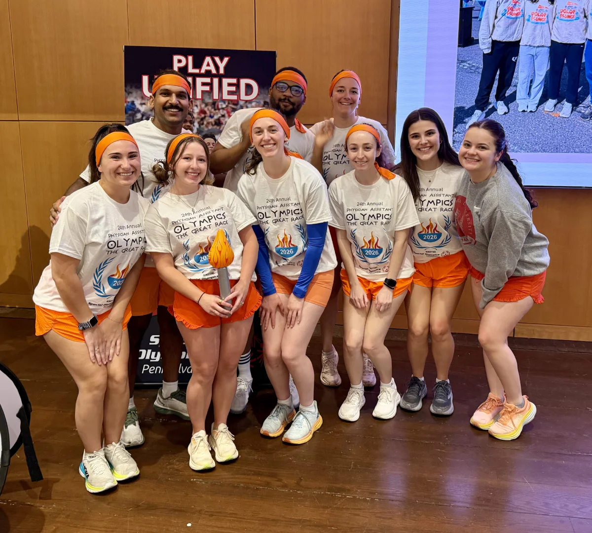 A group of students wearing PA Olympics related shirts and smiling for a photo. The shirts read: 24th Annual Physician Assistant Olympics, The Great Race, 2026.