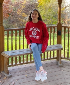 Honors Convocation 2025 award recipient Payton Ryan Goltz sits in a gazebo on a wood bench with her legs crossed and smiles.