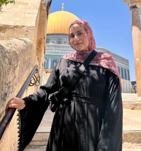 Honors Convocation 2026 award recipient Razan Ismail leans on a railing and smiles with the Dome of the Rock visible in the background.