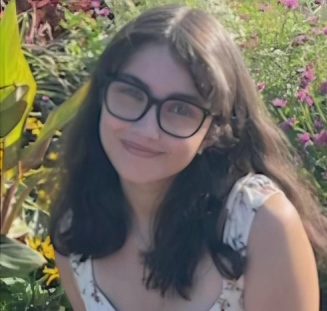 Honors Convocation 2025 award recipient Rosalena Esperanza Garcia sits outside surrounded by flowers and smiles.