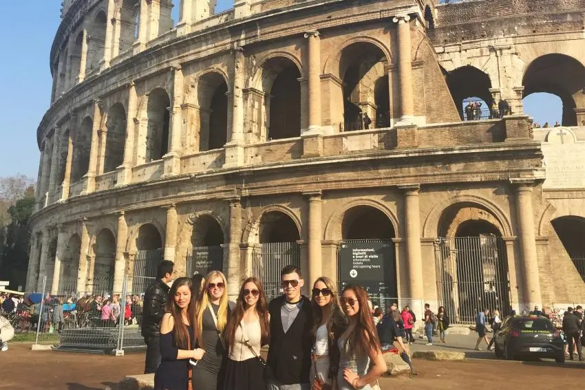 Six people posing outside of the Colosseum in Rome.