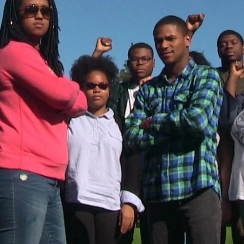 Photo of focused students posing on Haber Green making the power sign.