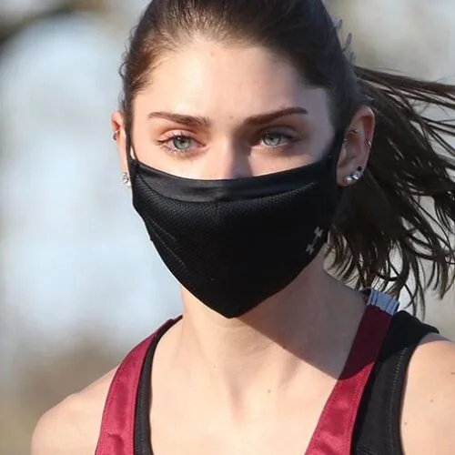 Female student jogging with a black mask on.