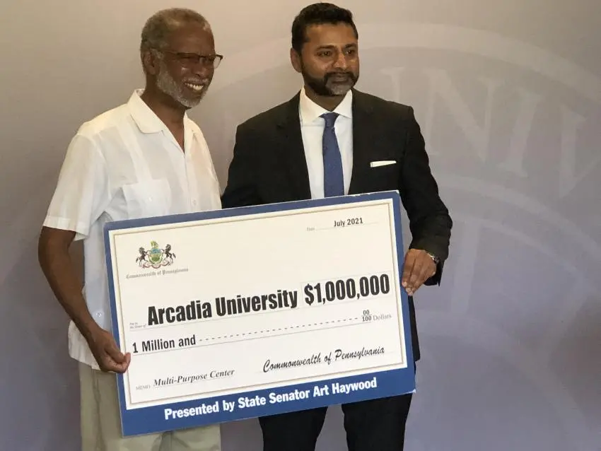 A man presents Arcadia's President Nair with a large check for one million dollars