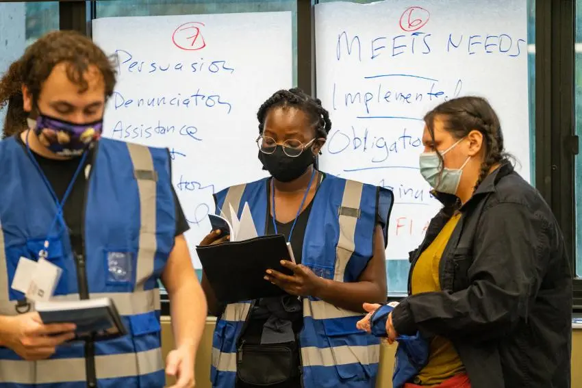 Three masked students with blue vests participating in the simulation.