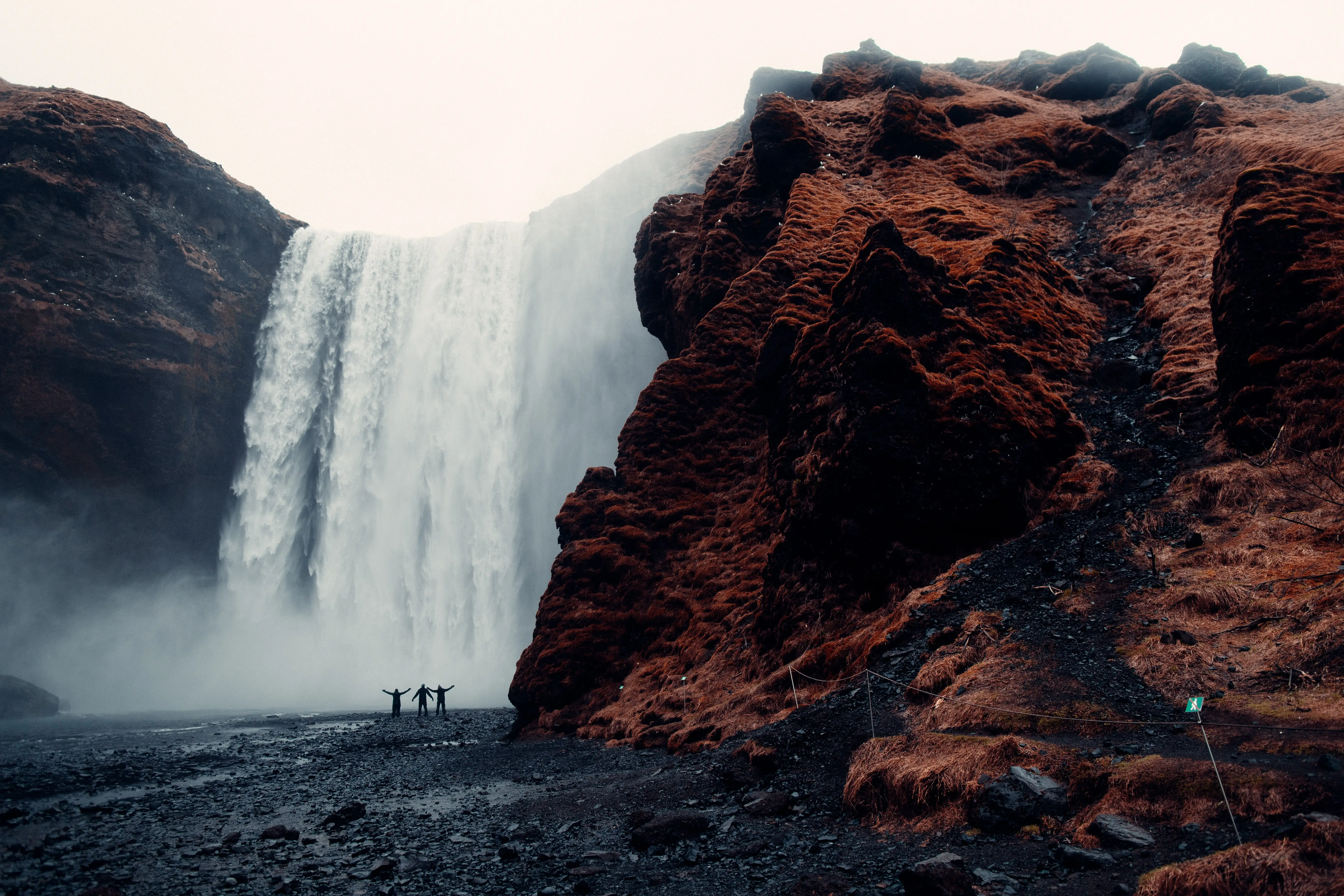 people in front of a waterfall and bare cliffs