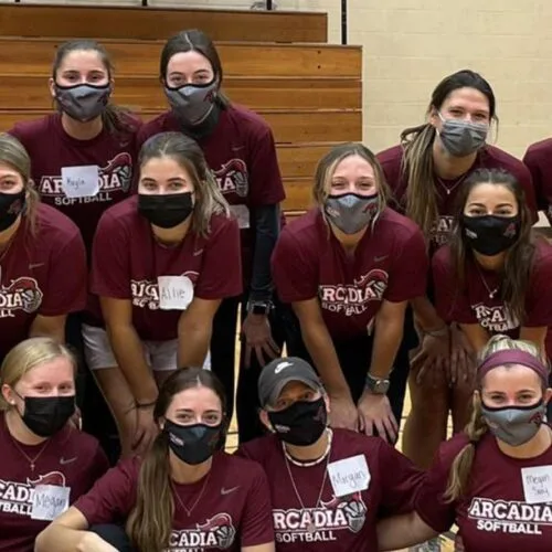 Masked Arcadia girls sports team poses in a huddle in the gym