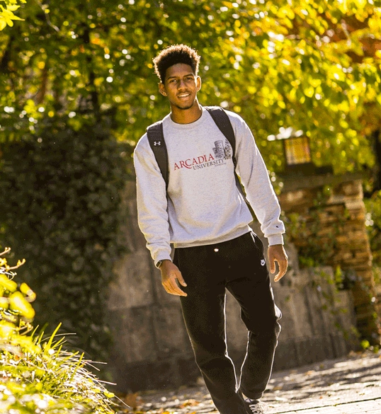 Student in Arcadia sweatshirt walking and smiling