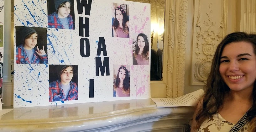 An image of s student standing next to a collage of themselves, one side pink and the other side blue. The collage reads "Who Am I"