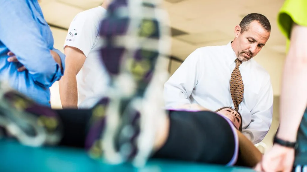 A physical therapy professor demonstrates an examination on a student.