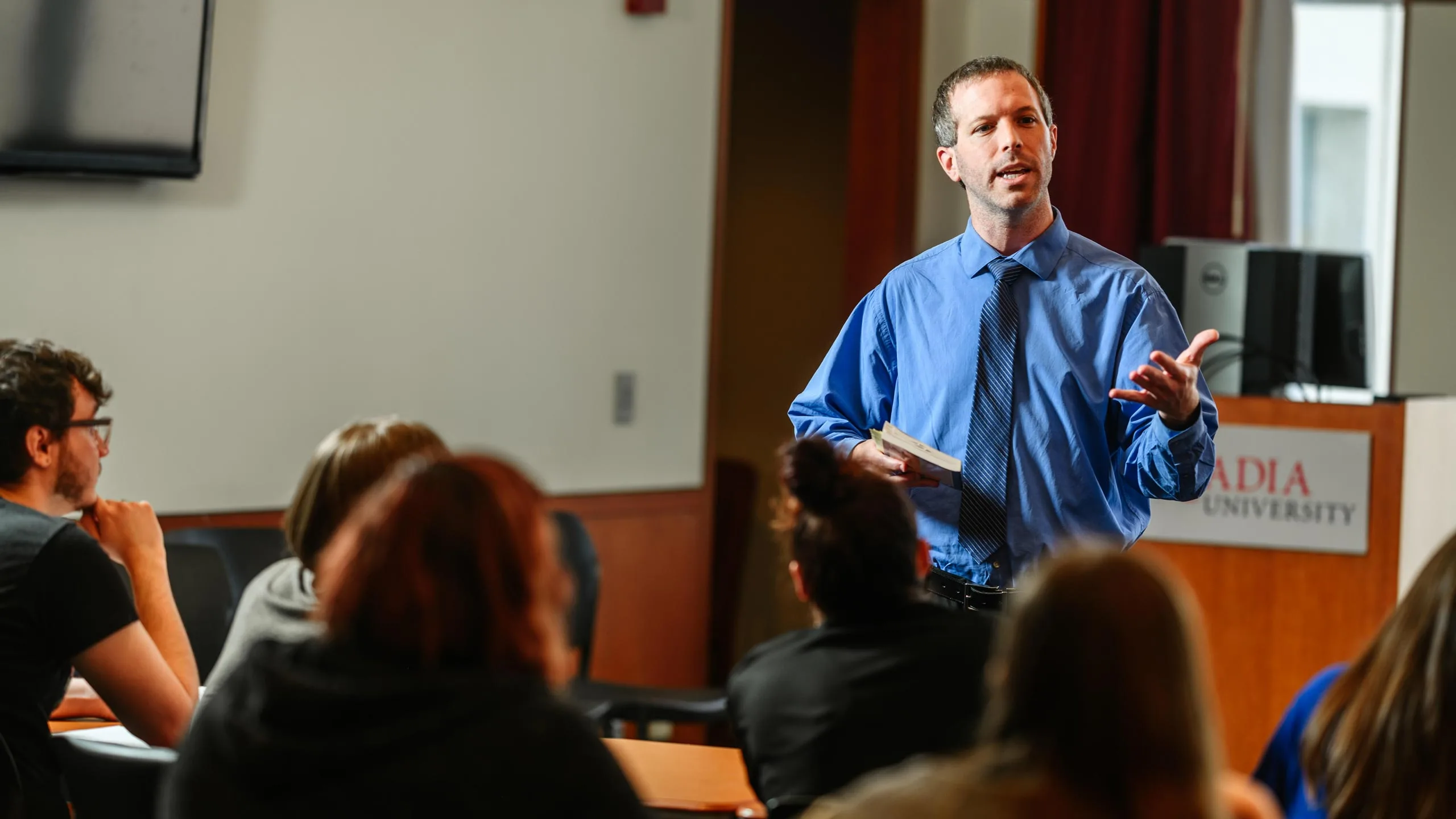 An English professor presents a lecture to a classroom full of students.