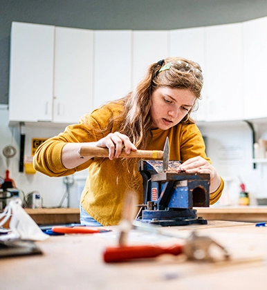 A student works on a class project with a hammer.