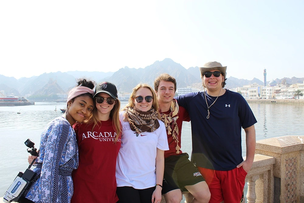 Group of five Arcadia students smiling at the camera during trip abroad.