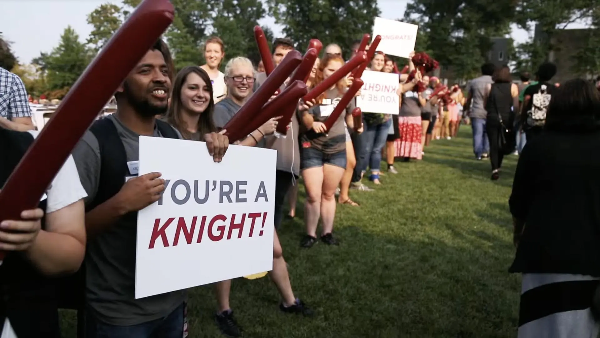 Transfer students show their Knight spirit at an outdoor event by holding white posters that read 