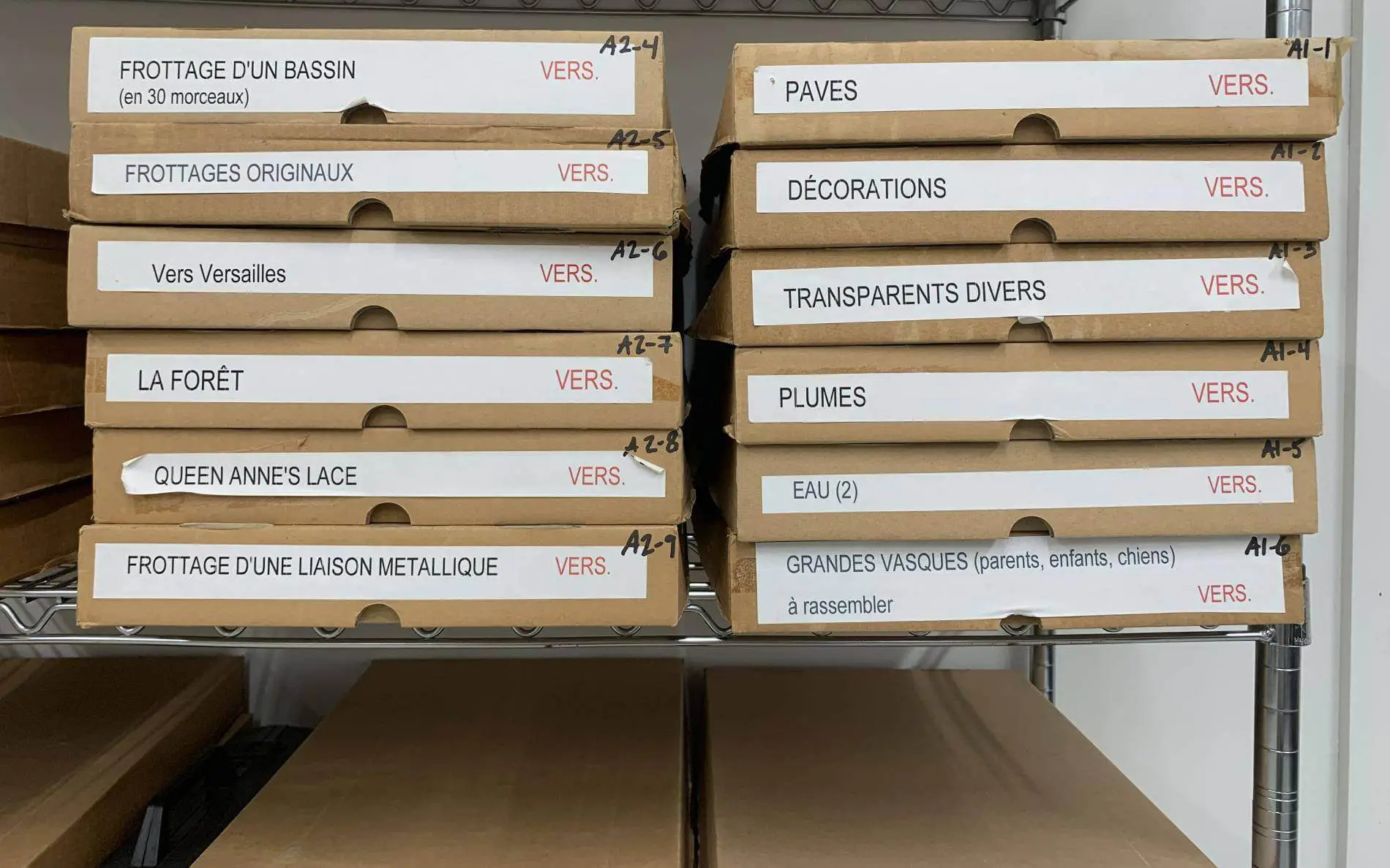 Two piles of boxes labeled with the names of Pati Hill's artwork on paper.