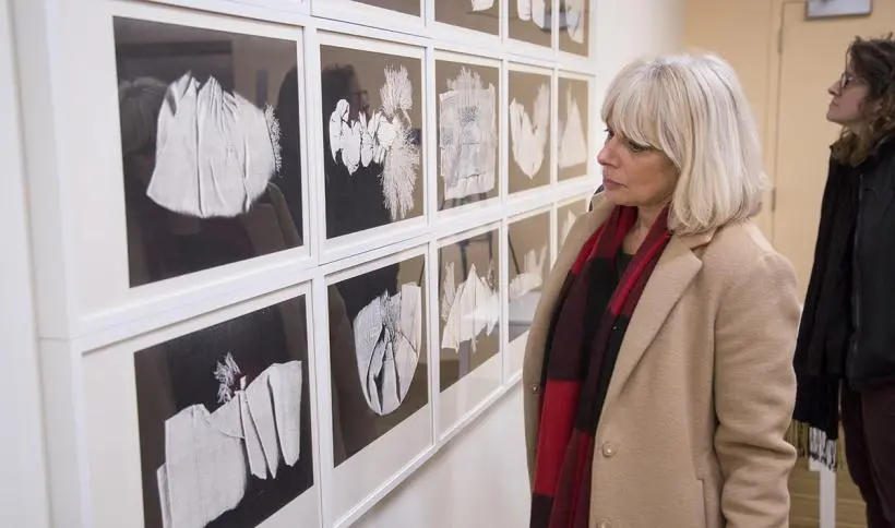 A woman views a series of Pati Hill's photocopies installed on gallery wall.