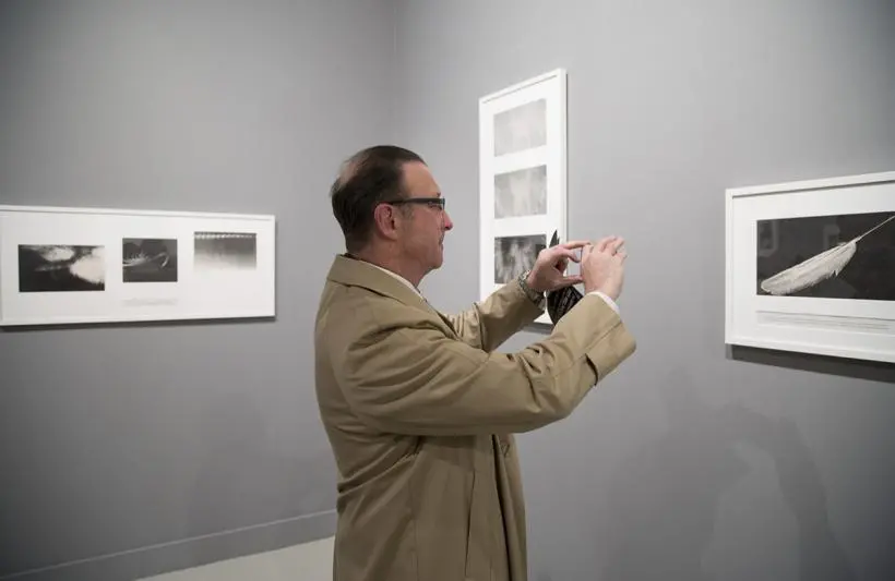 A visitor taking a photograph of the exhibition with his phone.
