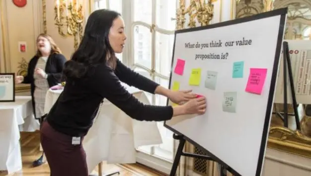 A woman putting sticky notes on a presentation board.