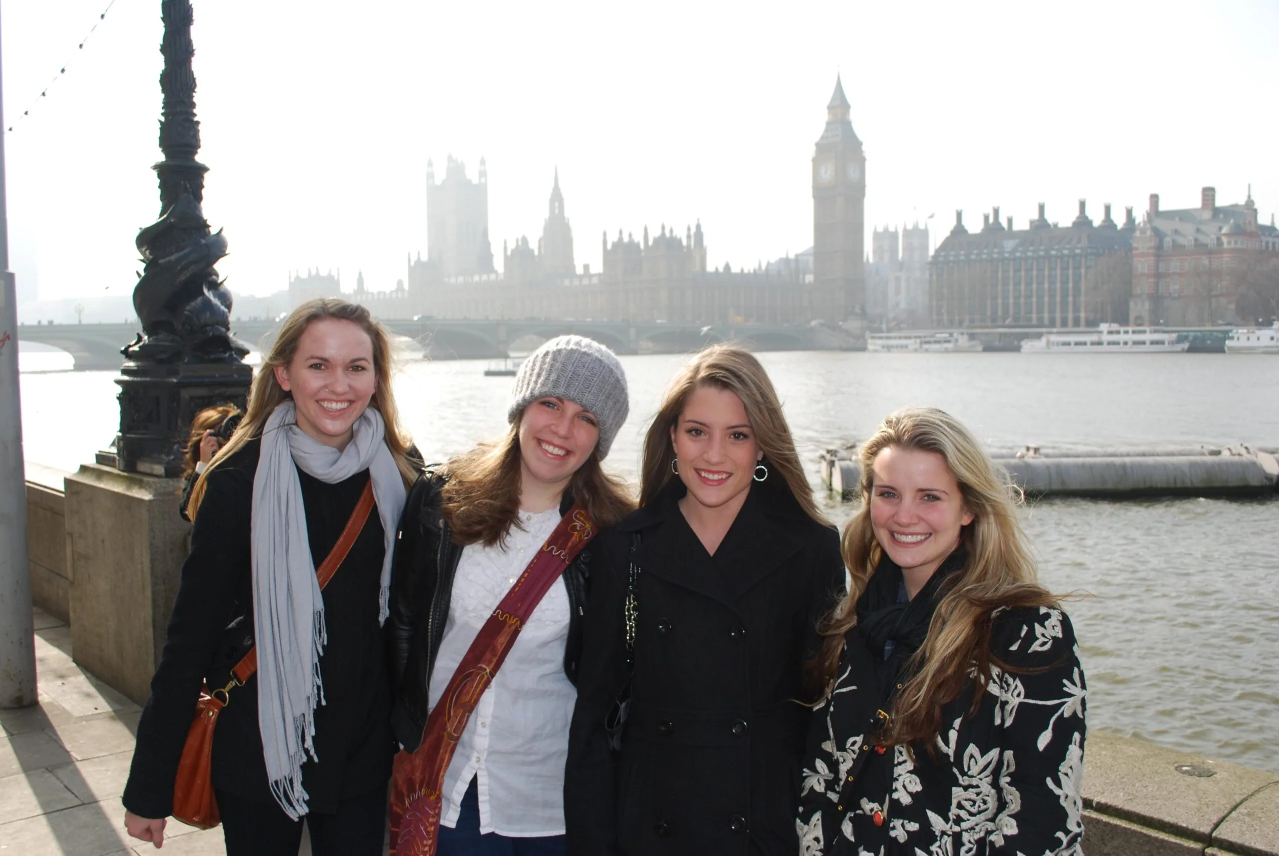 Four students smiling at the camera with London, England in the background.