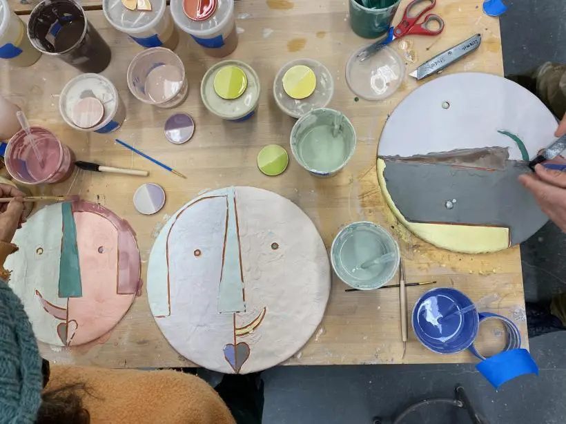 Ceramicists painting glaze on their artwork.