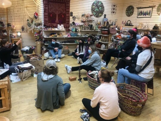 A group of people sitting together in a room full of pottery-like objects