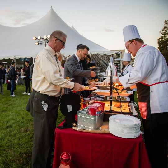 Workers prepare food at a catering function by Metz