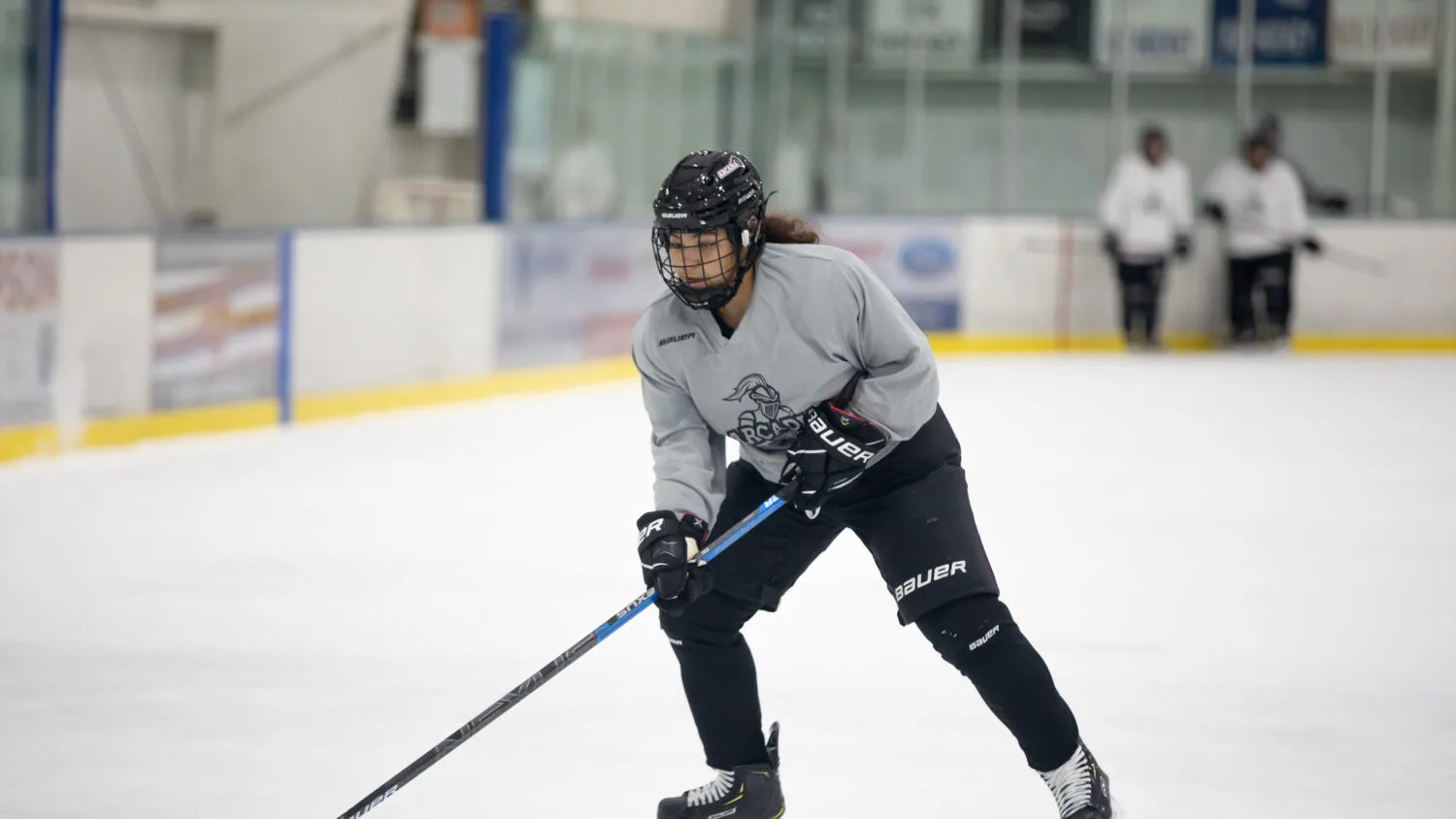 Student playing hockey in an ice rink.