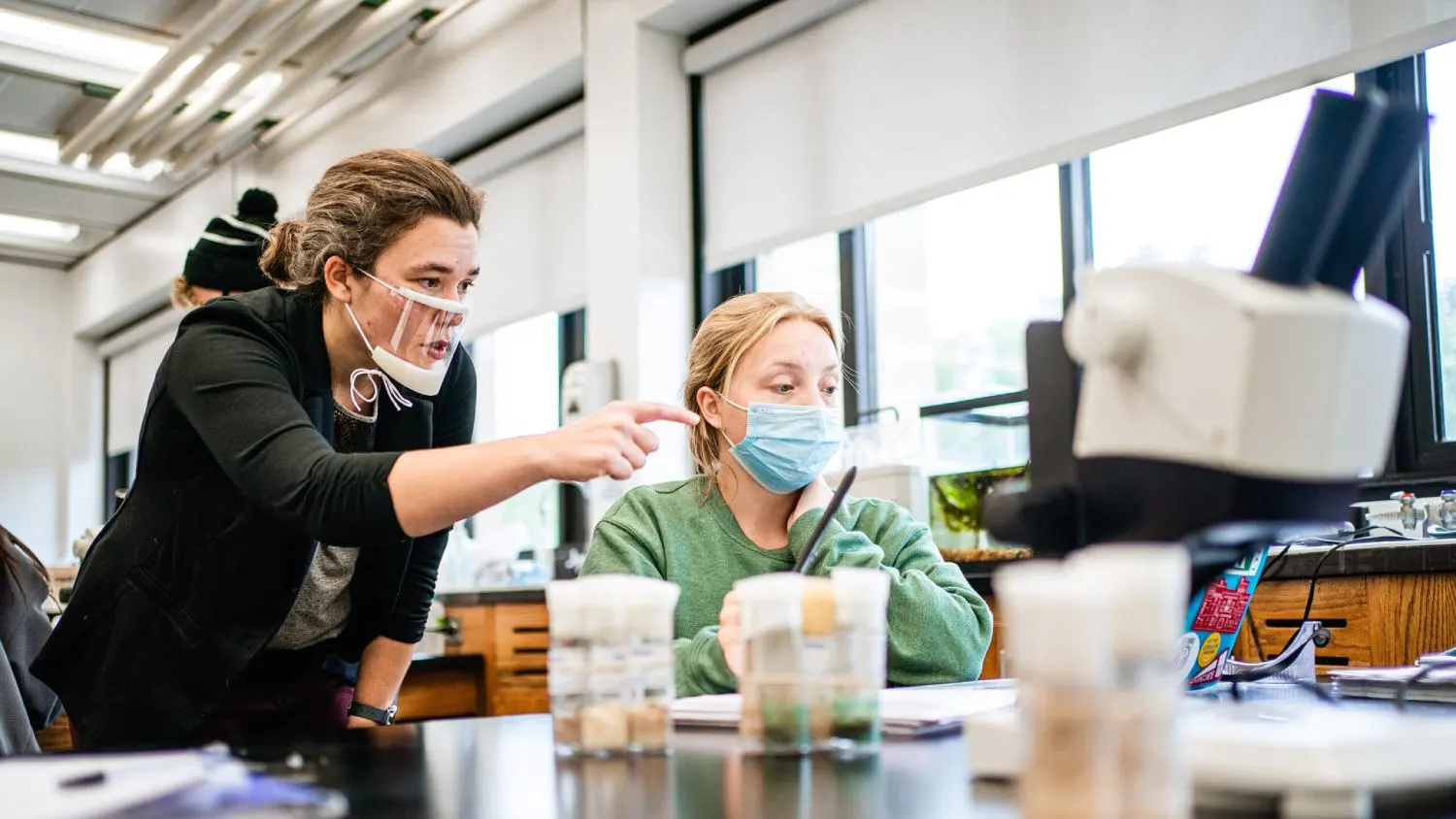 An instructor and student work in a lab on a biology project.