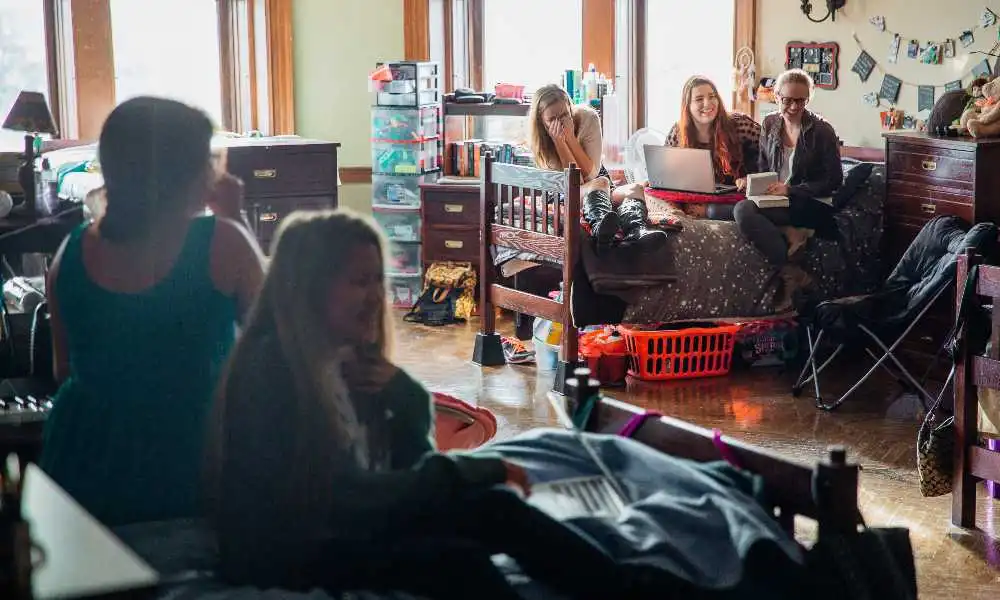 A group of female students laugh in a castle dorm room.