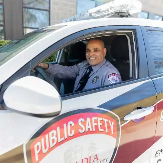 Public Safety officer smiling at the camera from his patrol car.