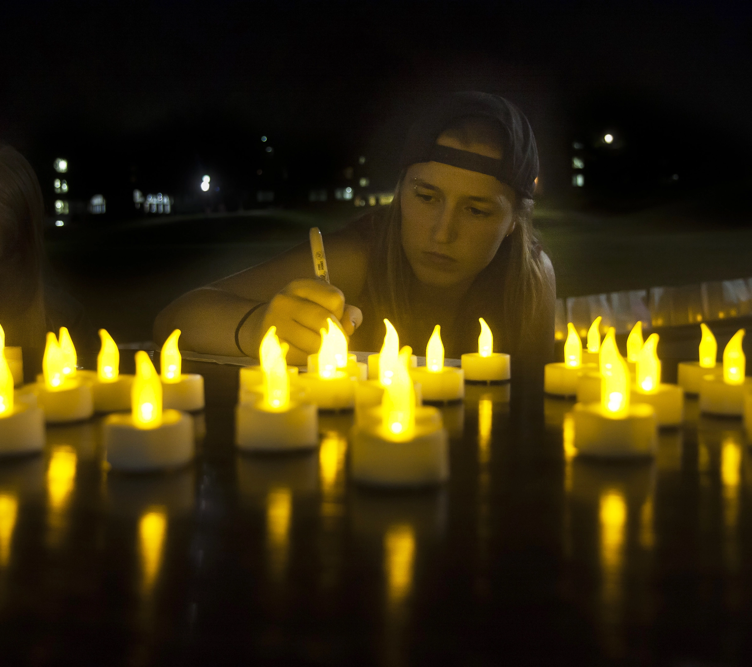 Students writes note on paper in front of candles during a remembrance event in honor of the shooting at Pulse Night Club.