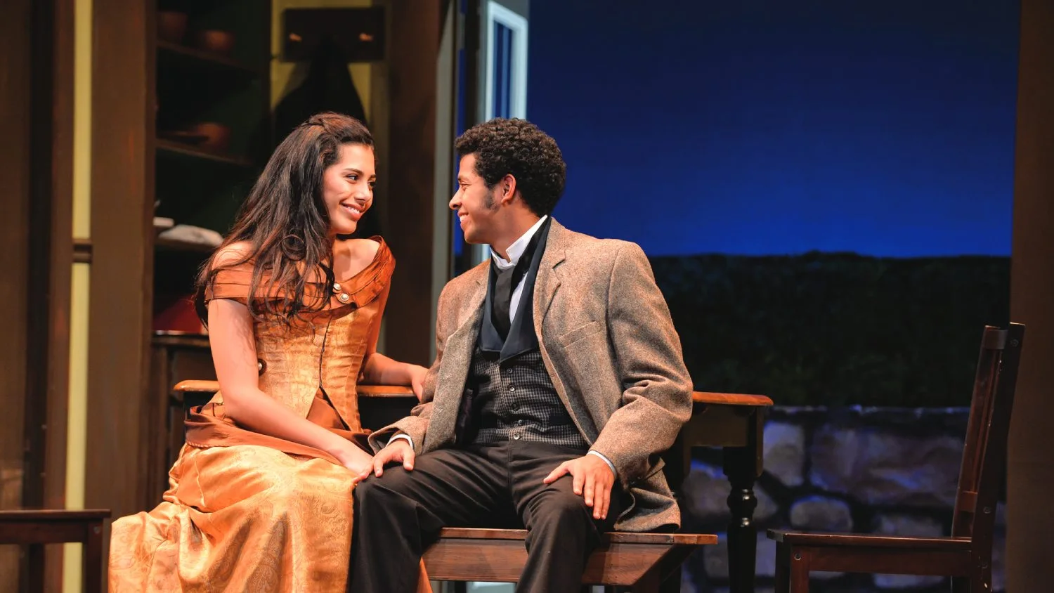 Two students perform on stage while wearing historical costumes.