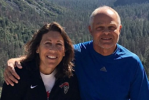 Two alumni in front of a mountain smiling at the camera.