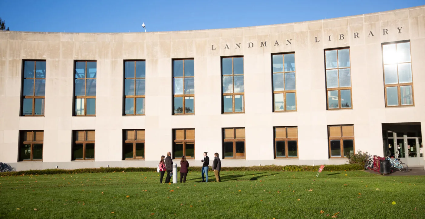 An outside view of the Landman Library with students walking by.
