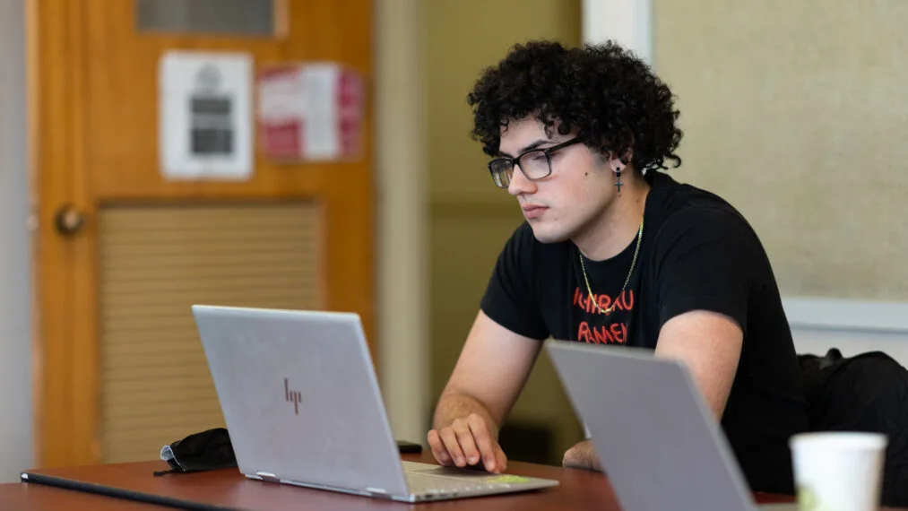 A student works on a laptop in a classroom.